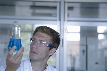 年轻的男科学家在实验室里举着烧瓶