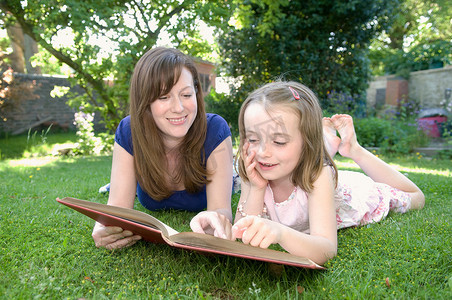 困难儿童摄影照片_妇女和儿童一起从书中阅读