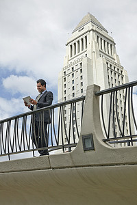 美国加利福尼亚州洛杉矶市政厅一名商人站在人行道上看着数字平板电脑