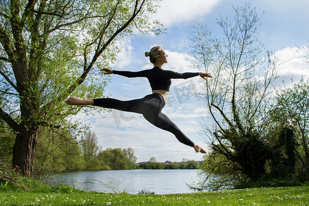 年轻的女舞者在湖边跳半空