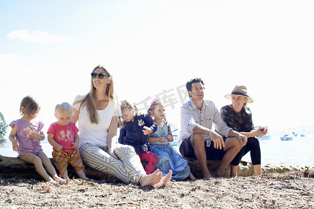 新西兰海滩家人和女儿坐在树干上