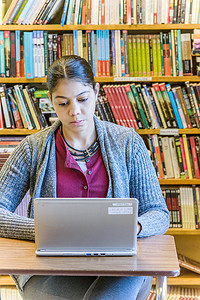 成年女学生在图书馆使用笔记本电脑