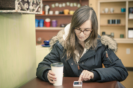 中年女性在咖啡馆用智能手机发短信