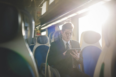 火车上使用数字平板电脑的年轻商人的肖像