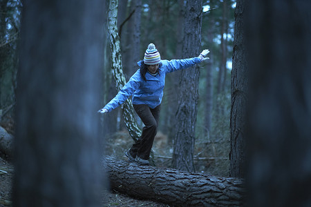 女徒步旅行者在森林中倒下的树上保持平衡