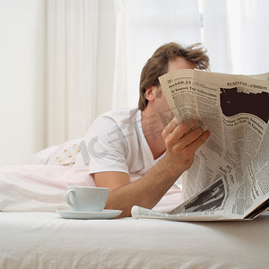 男人躺在床上手里拿着茶和纸