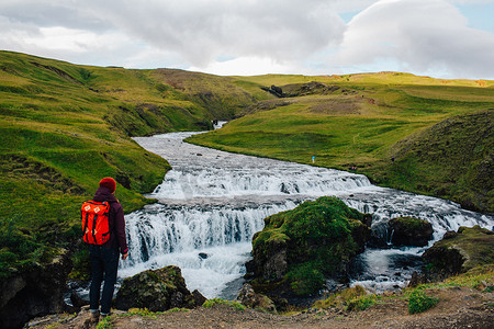 中年男子看着流经郁郁葱葱的绿色景观的河流的背影冰岛