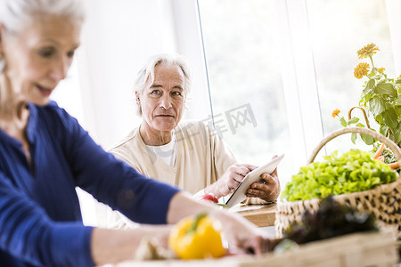 老年夫妇在厨房柜台使用数字平板电脑准备食物