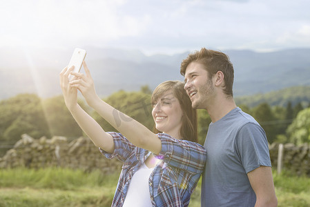 晴朗的天空下年轻夫妇在农村用手机自拍
