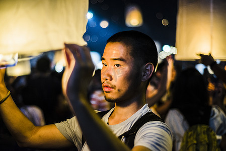 泰国清迈一名年轻男子手持点燃的纸灯笼等待放飞