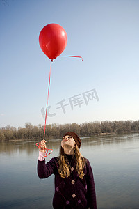 河边的女孩抬头看着气球