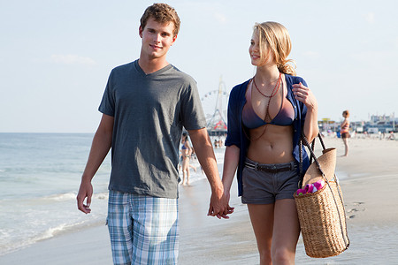 爱情发生摄影照片_十几岁的情侣手牵手走在海滩上