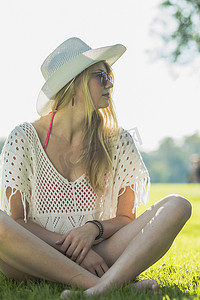 戴着白色太阳帽的年轻女子盘腿坐着