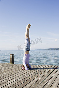 海边码头上的成熟女子头顶着地保持平衡