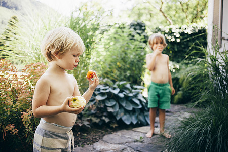 在花园小路上吃苹果和橙子的男孩布卢登茨奥地利