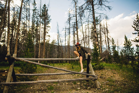 美国科罗拉多州落基山国家公园森林中的妇女在木结构上攀登