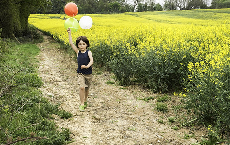 男孩在黄色花田跑道上拉气球