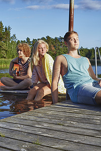三个年轻的成年朋友在瑞典加夫勒的码头上放松