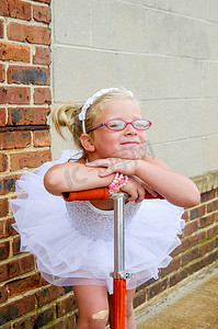 小女孩穿芭蕾舞裙靠在滑板车把手上的肖像