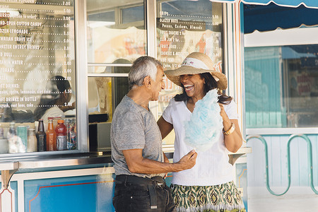 美国加利福尼亚州长滩一对老年夫妇站在茶点摊旁手里拿着棉花糖