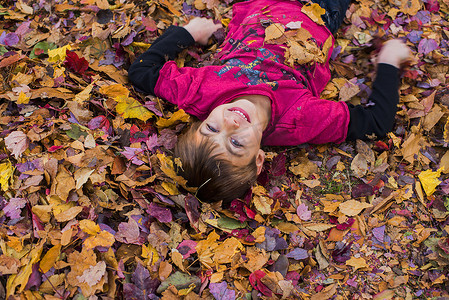 逃生演习摄影照片_躺在秋叶里的小男孩