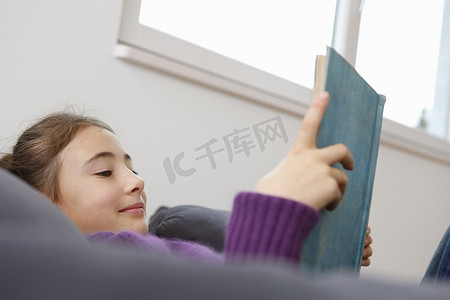 女孩躺着看书微笑的低视角