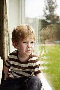 室内望向窗外摄影照片_男孩望着窗外的后院