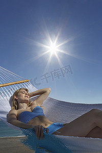 美国佛罗里达州迈阿密海滩一名年轻女子躺在阳光下的吊床上