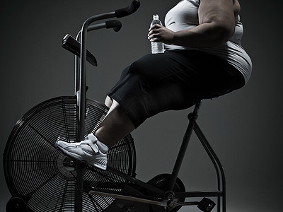 大药瓶摄影照片_骑健身车的超重女性