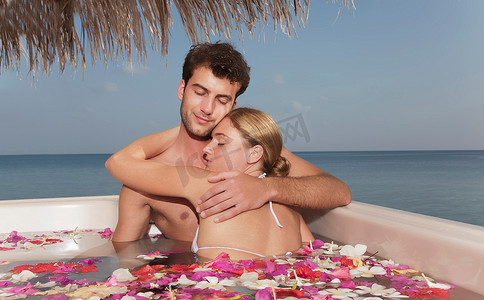 水面花瓣摄影照片_一对情侣在泳池里用花瓣拥抱