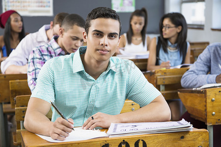 男学生肖像坐在教室的书桌前