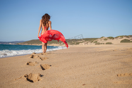 意大利撒丁岛皮斯西纳斯海滩上的女人背着纱笼