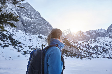 奥地利一名年轻女子在雪地中徒步旅行在山顶上看太阳