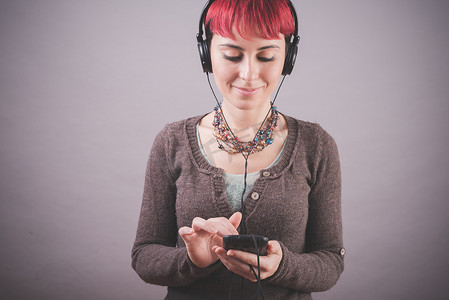 工作室里粉色短发的年轻女子在智能手机上选择音乐