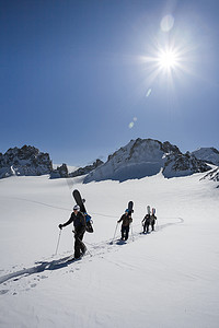 山水人摄影照片_四名男性滑雪板运动员徒步穿越瑞士阿尔卑斯山特里恩特积雪覆盖的风景
