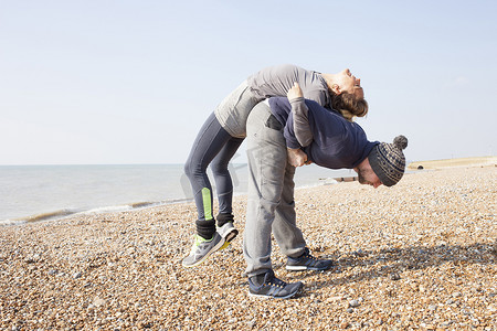 男女热身训练布莱顿海滩背靠背举重