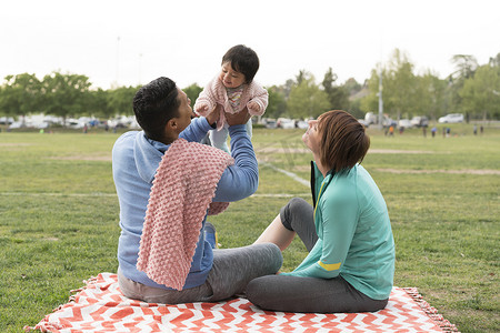 一对夫妇在公园里带着婴儿玩耍