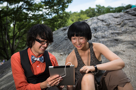 年轻夫妇戴着耳机使用平板电脑