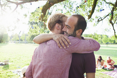 两个年轻人在公园的派对上拥抱在一起
