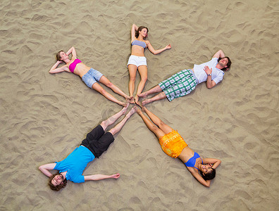环绕五角星摄影照片_朋友们以星形躺在沙滩上的鸟瞰