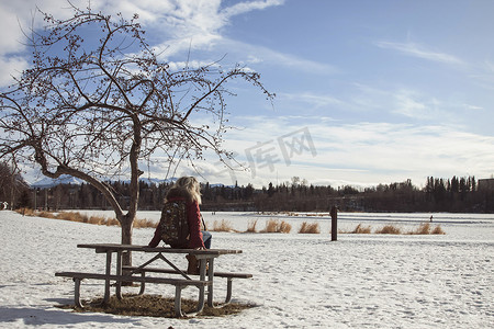 野餐桌摄影照片_阿拉斯加安克雷奇坐在野餐长凳上的年轻女子