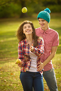 一对十几岁的夫妇在公园里玩苹果