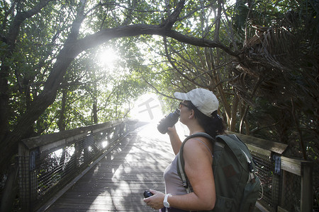 美国佛罗里达州北棕榈滩一名女徒步旅行者在阳光普照的人行桥上喝水瓶
