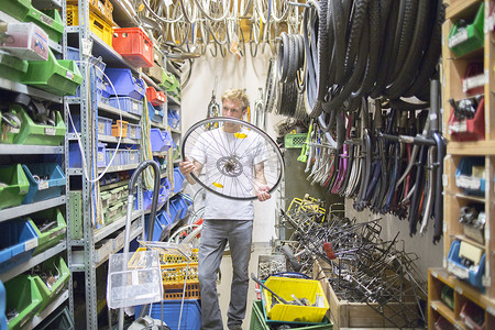汽车修理店摄影照片_储藏室里的中年男子手持自行车轮子
