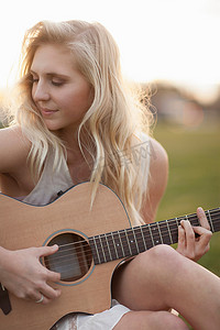 在草地上弹吉他的女人