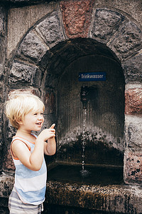 男孩站在石头饮水机旁的侧视布卢登茨奥地利沃拉尔伯格