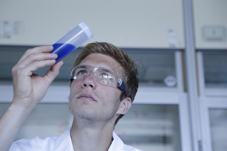 化学思考摄影照片_男科学家在实验室抬头看塑料瓶里的样品
