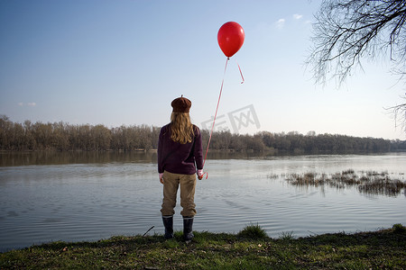 拿着红色气球的河边女孩