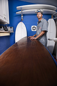 汽车修理店摄影照片_工作室里的一位中年男子和冲浪板的肖像