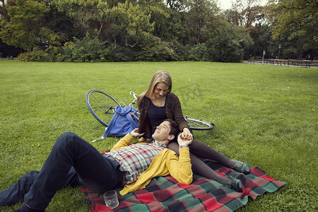 公园里的一对年轻夫妇手牵着野餐毯子